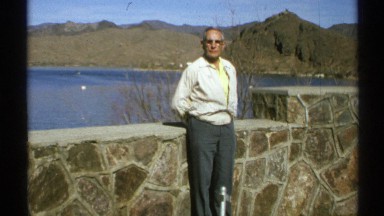 1972: an elderly person wearing sun glass standing in front of a riverside on a
