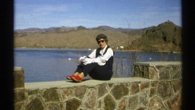 1972: a woman sits on a wide wall, looking at the camera she is saying