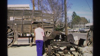 1972: a lady in blue and pink stands near a wagon outside. ARIZONA
