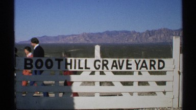 1972: A White Gate with 'Boot Hill Graveyard' Sign on a Sunny Day