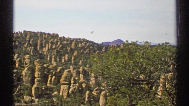 1972: on a sunny day viewing large rock formations and green plants all around.