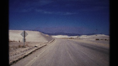 1972: a long dry road without trees and plants and only one road sign at the