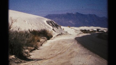 1972: snow-covered path curves between snowy slope and raised darker ground NEW