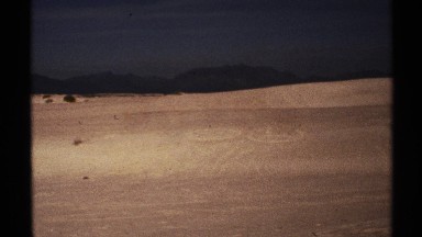 1972: a smiley face and a frowny face drawn into the sand by a group of people.