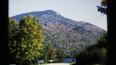 1971: car appears on country road at bend by river flowing at mountain base NEW