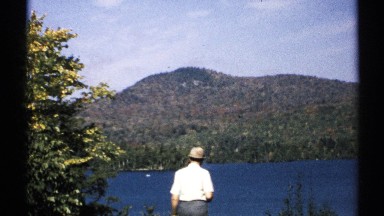 1971: man takes a few steps toward blue lake from elevated vantage point NEW