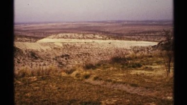 1972: car drives straight in barren region with earth tones separating areas NEW