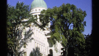 1971: a still shot of the colt armory in hartford ct, behind trees on a sunny