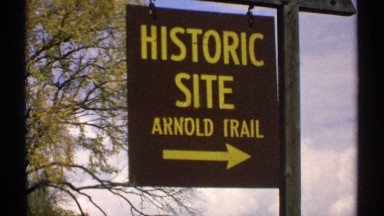 1971: brown and yellow historical site sign that points to the lake. MAINE