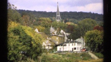 1971: Cars Drive on Road Cutting Across Slope Below Right Angled Buildings MAINE