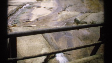 1971: a bridge overlooks water as it runs down a rocky clearing in an autumn