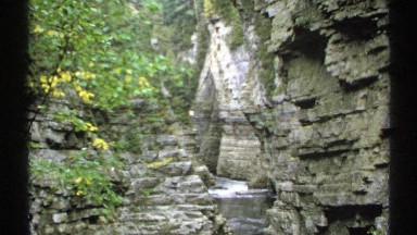 1971: a small river running between large rock formations with frothy water NEW
