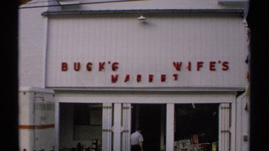 1971: roadside car are passing by in front of market entrance of buck's wife's