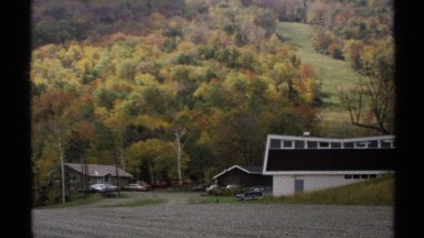 1971: houses are at mountain base below yellow, green and orange trees VERMONT