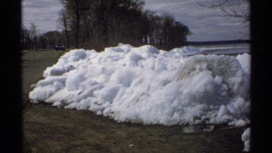 1970: a dark colored vehicle is driving across an open stretch of land during
