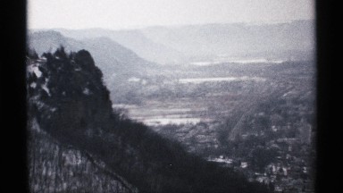 1971: wide street runs through valley town at the base of sloped mountains LA