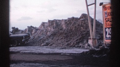 1971: car parked near de-icing salt pile and signage for salt being sold at