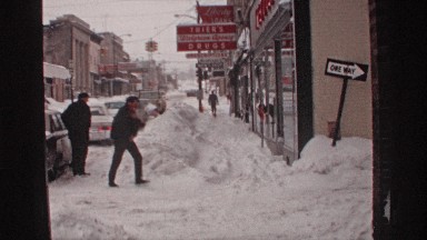 1971: a man runs down a snow covered sidewalk in a business district WISCONSIN