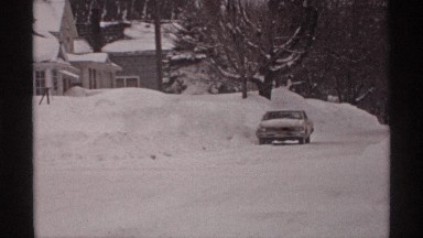 1971: snowy day a road covered with snow with a standstill vehicle parked beside