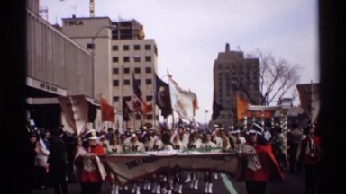 1971: Parade Procession of People Walking Behind a National Bank Banner