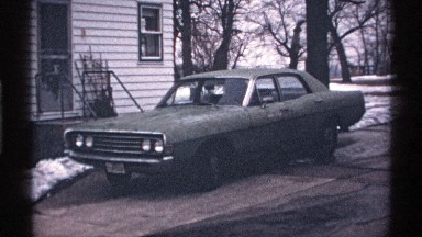 1971: a green car parked in a snowy driveway in a quiet neighborhood WISCONSIN