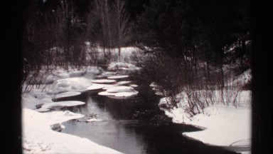 1971: a slow moving creek runs through a snow covered wooded area WISCONSIN
