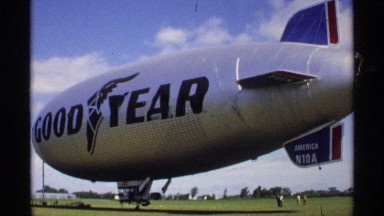 1970: a view of a goodyear blimp preparing for take off from a grassy field on a