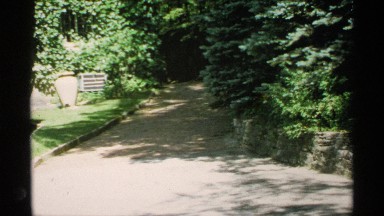1970: person wanders alone on an empty paved walkway surrounded by beautiful