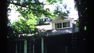 1970: ladder rests against front of house near dormer under extending branch