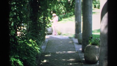 1970: an old woman walking through an aisle surrounded by many plants MINNESOTA
