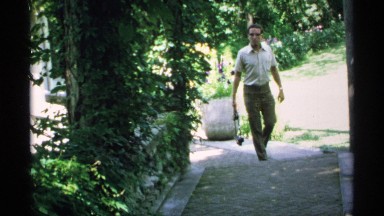 1970: a man with a small bag and walking at the ground and trees plants are