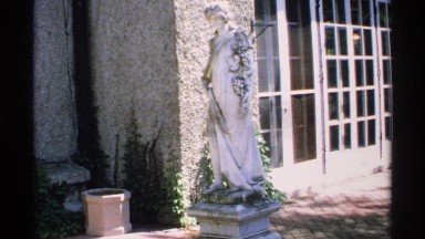 1970: a stone women sculpture is created in front of a luxury house, front door
