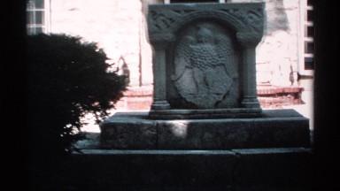 1970: a stone sign in front of a landmark, a bird like sculpture created on a