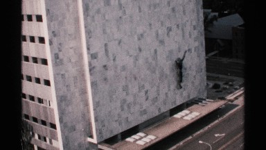 1970: tall building with red sedan driving by MINNESOTA