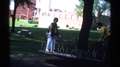 1970: a man and a woman having fun as if they were children on a mechanical game