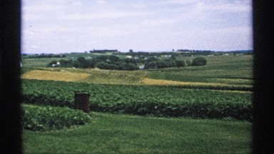 1970: this is a wide angle view of vast farm land on a somewhat cloudy day.