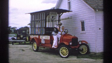 1970: a man and woman sit in a comical jail on wheels built on an antique car
