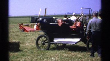 1971: women and men walk and stand near antique convertible car on display