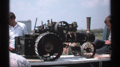 1971: boy watching a model of train with wheels, pipes, etc put up on a platform