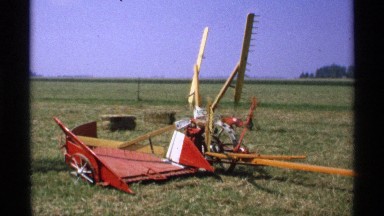 1971: showing a piece of equipment that is used on the farm. there are hay bales
