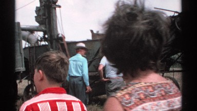 1971: group of people gathered around a vintage machine in the middle of the