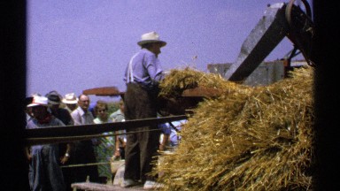 1971: a farmer standing operating a hay machine. MINNESOTA