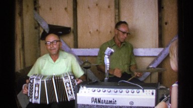 1971: two men showing off their band's musical talents while a young child