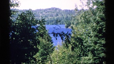 1972: a body of water spied at a distance through some trees ISLE ROYALE