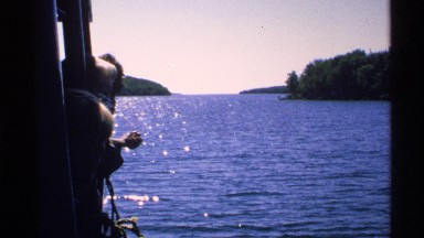 1972: a group of passengers gazing over the boat's edge, admiring the scenery