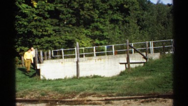1971: Two Men Walk Around a Concrete Structure with Steel Railings Adjacent to a
