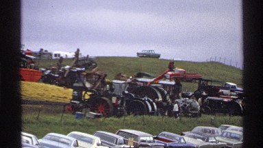 1971: Group of Vehicles in an Open Area with People Walking in Rollag