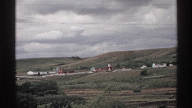 1972: beautiful view towards the mountains with small houses and clouds that