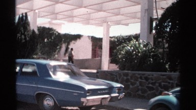 1975: man leaning against one of the many parked antique cars in front of a