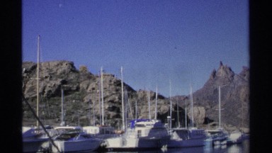 1975: boats on steady water with a rocky mountain scene in the background.